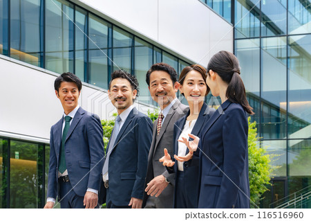 A group of executive male and female business people having a conversation in front of an office building 116516960