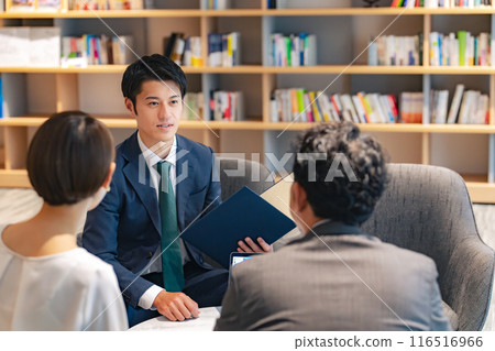A middle-aged couple and a counselor having a conversation in the lobby 116516966