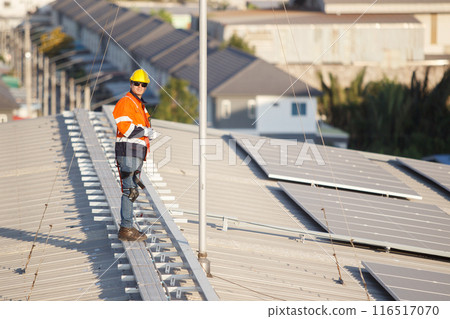Professional electric engineers survey and inspect solar panels installation on the factory metal sheet roof top, electric engineer team inspecting and check solar cell system. 116517070