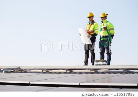 Professional electric engineers survey and inspect solar panels installation on the factory metal sheet roof top, electric engineer team inspecting and check solar cell system. 116517082