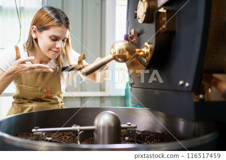 Professional coffee roaster working with modern automated roasting machine in the coffee roasting factory. Food and beverage business concept. Professional coffee roaster working with modern automated roasting machine in the coffee roasting factory. Food and beverage business concept. 116517459