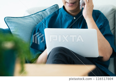 Middle-aged man talking on smartphone on sofa 116517804