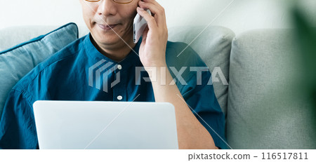 Middle-aged man talking on smartphone on sofa 116517811