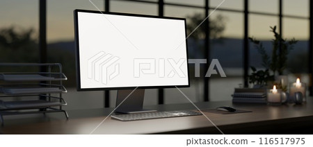 A computer with a white-screen mockup on a table against the window in a modern dark office at dusk. A computer with a white-screen mockup on a table against the window in a modern dark office at dusk. 116517975