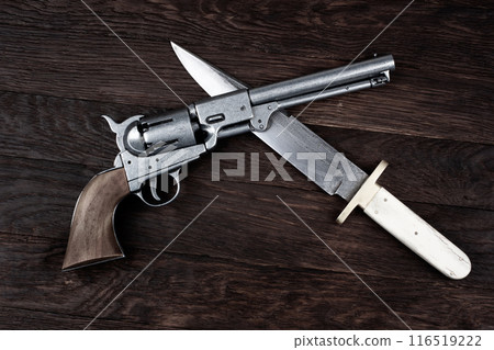 Old West Revolver with bowie knife on wooden deck. Old West Revolver with bowie knife on wooden deck. 116519222