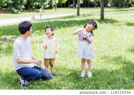 父母和孩子在清新的綠色公園玩泡泡 116519356