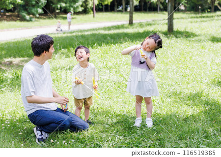 Parents and children playing with soap bubbles in a park with fresh greenery 116519385