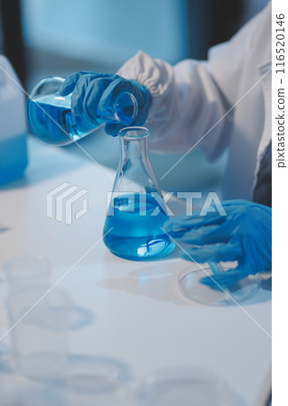 Group of dedicated scientist conduct chemical experiment in medical laboratory, carefully drop precise amount of liquid from pipette into test tube for vaccine drug or antibiotic development. Neoteric 116520146