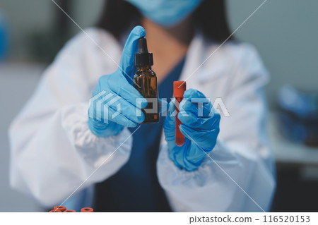 Group of dedicated scientist conduct chemical experiment in medical laboratory, carefully drop precise amount of liquid from pipette into test tube for vaccine drug or antibiotic development. Neoteric 116520153