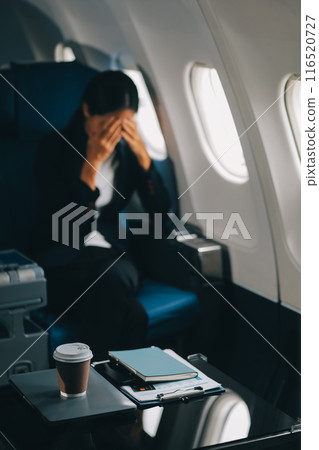 Young business woman sitting inside plane at the airport with sky view from the window drinking a cup of coffee 116520727