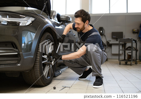 Mechanic working on car wheel in garage workshop 116521196