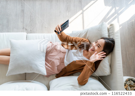 High angle view of happy cheerful positive young Asian woman on the phone at home 116522433