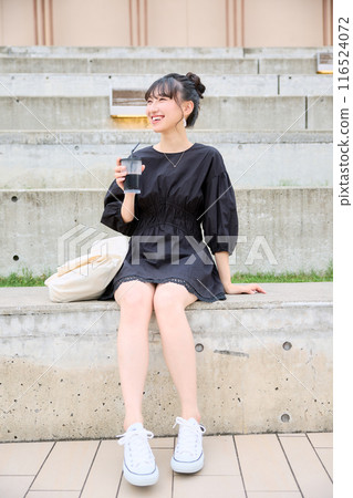 Female college student drinking coffee on a bench 116524072