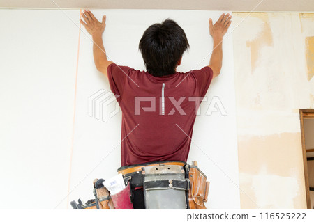 A craftsman laying wallpaper during the renovation of a used house 116525222