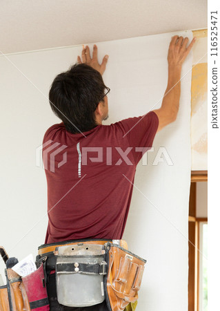 A craftsman laying wallpaper during the renovation of a used house 116525471