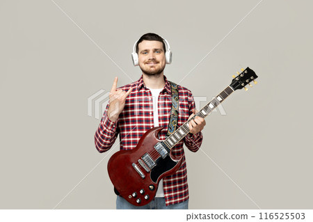 Attractive young guy in headphones and with a guitar 116525503