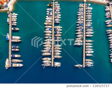 Scenic aerial view many yachts boats moored at Croatian bay harbor shore blue turquoise clear water at bright summer sunny day. Top above Mediterranean sea marina. Boat vessel charter service Scenic aerial view many yachts boats moored at Croatian bay harbor shore blue turquoise clear water at bright summer sunny day. Top above Mediterranean sea marina. Boat vessel charter service 116525717