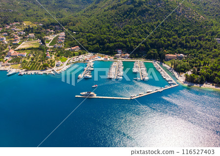 Scenic aerial view many yachts boats moored at Croatian bay harbor shore blue turquoise clear water at bright summer sunny day. Top above Mediterranean sea marina. Boat vessel charter service Scenic aerial view many yachts boats moored at Croatian bay harbor shore blue turquoise clear water at bright summer sunny day. Top above Mediterranean sea marina. Boat vessel charter service 116527403