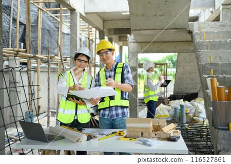 Specialists team in safety vest and helmet discussing structure of the building at construction site 116527861