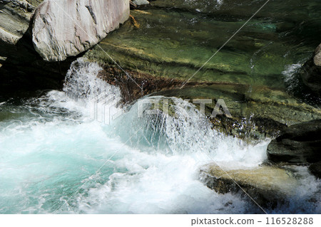 The clear waters of the Asemi River flowing through a valley of folded metamorphic rocks 116528288