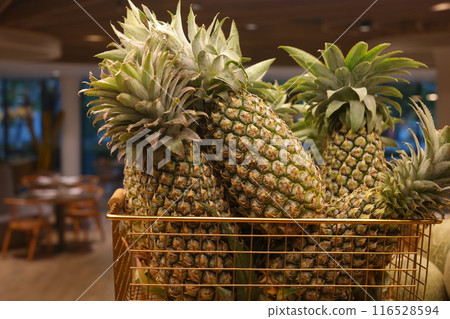 Pineapples in a basket on a shelf in a store Pineapples in a basket on a shelf in a store 116528594