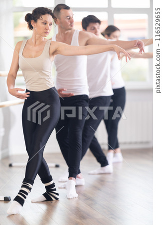 Woman performing demi rond de jambe at group barre training Woman performing demi rond de jambe at group barre training 116529655
