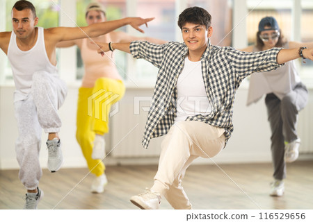 Young guy practicing hip hop reject step in training hall Young guy practicing hip hop reject step in training hall 116529656