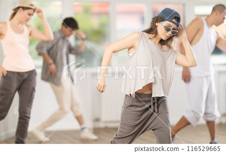 Young girl standing performs basic hip hop movements in front of group of students Young girl standing performs basic hip hop movements in front of group of students 116529665