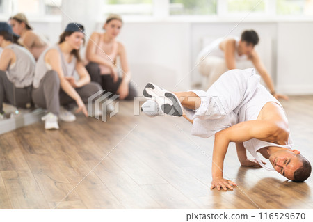 Young guy breakdancing in front of group members watching him Young guy breakdancing in front of group members watching him 116529670