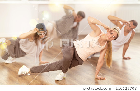 Concetrated guys and girls studying movement of contemporary dance in classroom with his friends 116529708