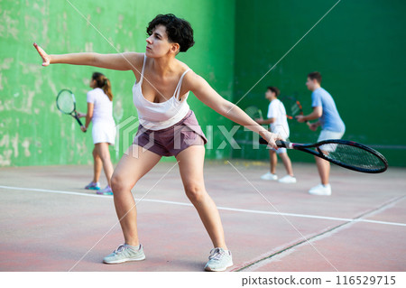 Sportive woman in shorts and t-shirt playing frontenis on court Sportive woman in shorts and t-shirt playing frontenis on court 116529715