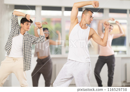 Young man standing performs basic hip hop movements in front of group of students Young man standing performs basic hip hop movements in front of group of students 116529738