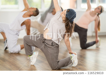 Girl and her students perform hip hop dance on one bent leg, movement in horizontal plane near floor Girl and her students perform hip hop dance on one bent leg, movement in horizontal plane near floor 116529810