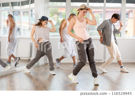 Young girl standing performs basic hip hop movements in front of group of students Young girl standing performs basic hip hop movements in front of group of students 116529945