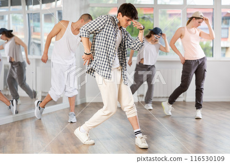 Young man standing performs basic hip hop movements in front of group of students 116530109