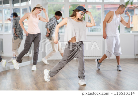 Young girl standing performs basic hip hop movements in front of group of students Young girl standing performs basic hip hop movements in front of group of students 116530114
