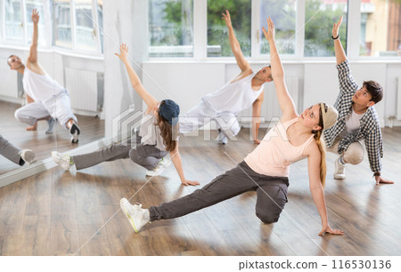Girl and her students perform hip hop dance on one bent leg, movement in horizontal plane near floor Girl and her students perform hip hop dance on one bent leg, movement in horizontal plane near floor 116530136