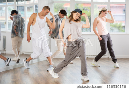 Young girl standing performs basic hip hop movements in front of group of students Young girl standing performs basic hip hop movements in front of group of students 116530156