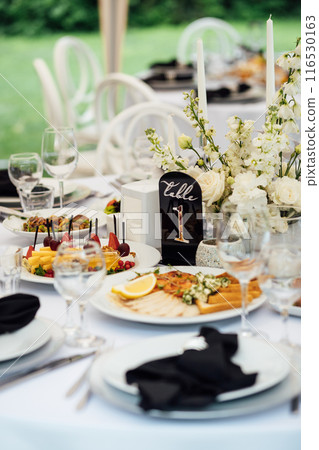 Luxurious restaurant. Luxurious interior, white tables, serving dishes and glasses for guests Luxurious restaurant. Luxurious interior, white tables, serving dishes and glasses for guests 116530163