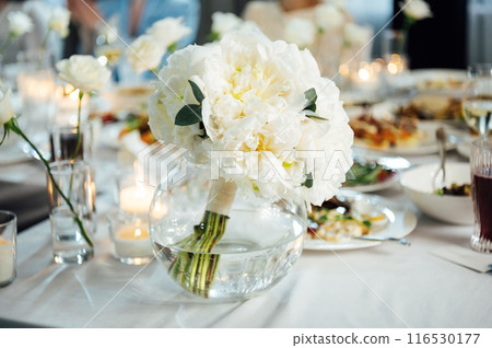 An incredibly beautiful wedding bouquet lies on the table during dinner. 116530177