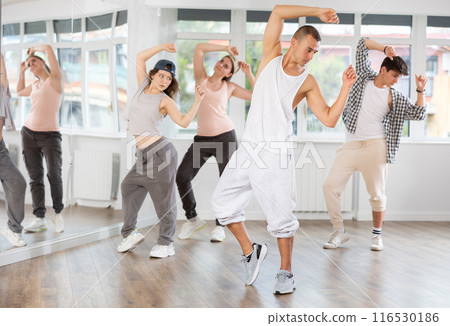 Young man standing performs basic hip hop movements in front of group of students 116530186