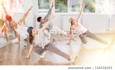 Concetrated guys and girls studying movement of contemporary dance in classroom with his friends Concetrated guys and girls studying movement of contemporary dance in classroom with his friends 116530203