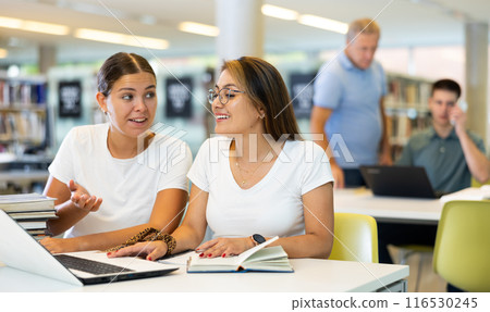 Portrait of female friends together in public library 116530245