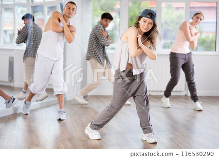 Young girl standing performs basic hip hop movements in front of group of students 116530290
