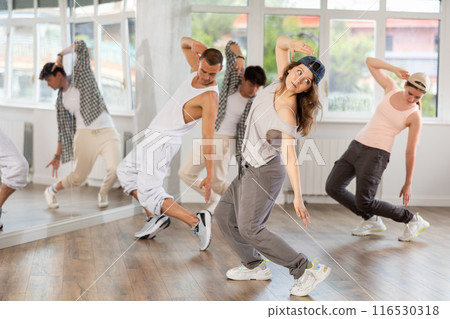 Young girl standing performs basic hip hop movements in front of group of students 116530318