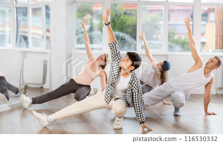 Concetrated guys and girls studying movement of contemporary dance in classroom with his friends 116530332