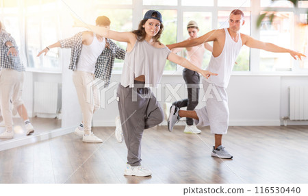 Young girl standing performs basic hip hop movements in front of group of students Young girl standing performs basic hip hop movements in front of group of students 116530440
