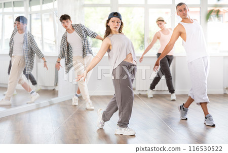 Young girl standing performs basic hip hop movements in front of group of students Young girl standing performs basic hip hop movements in front of group of students 116530522