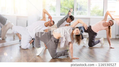 Girl and her students perform hip hop dance on one bent leg, movement in horizontal plane near floor Girl and her students perform hip hop dance on one bent leg, movement in horizontal plane near floor 116530527