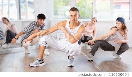 Teacher and her students squatting down and perform hip hop dance Teacher and her students squatting down and perform hip hop dance 116530604
